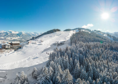 Allgaeuer Berghof Suedseite mit Blick auf die Skipiste- Luftaufnahme im Winter